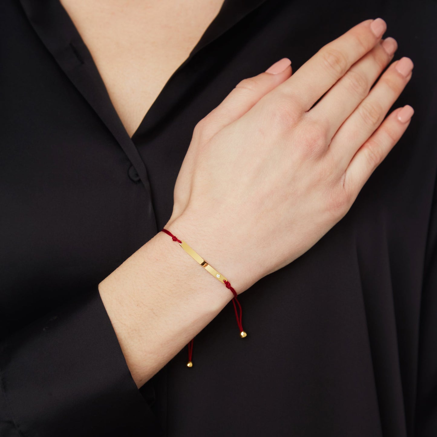 Engravable KT18 Yellow Gold and Diamond Tag Bracelet attached to a Cord.